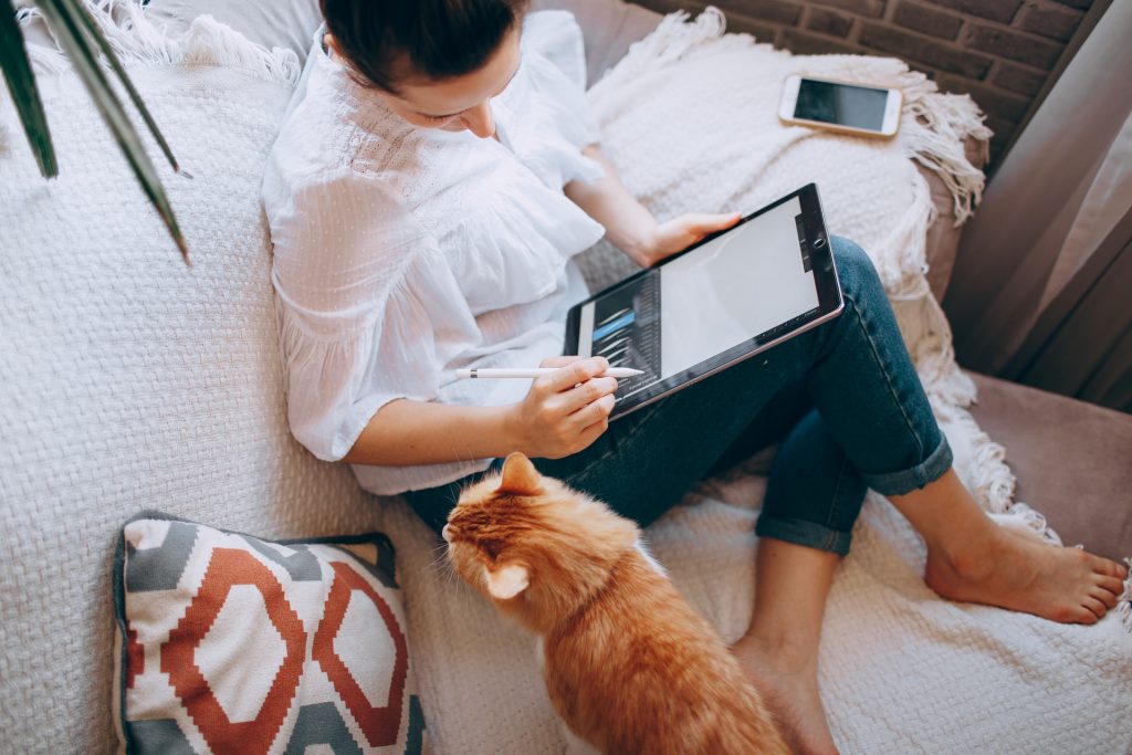 women sitting on bed and using tablet